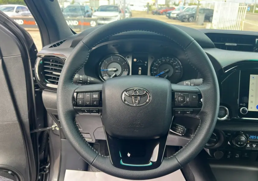 Vue rapprochée du volant et du tableau de bord du Toyota Hilux 2025 gris atlas, avec commandes intégrées et écran tactile.