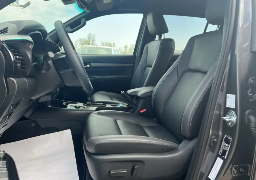Intérieur du Toyota Hilux 2025 gris atlas, vue côté conducteur montrant les sièges en cuir noir et le tableau de bord.