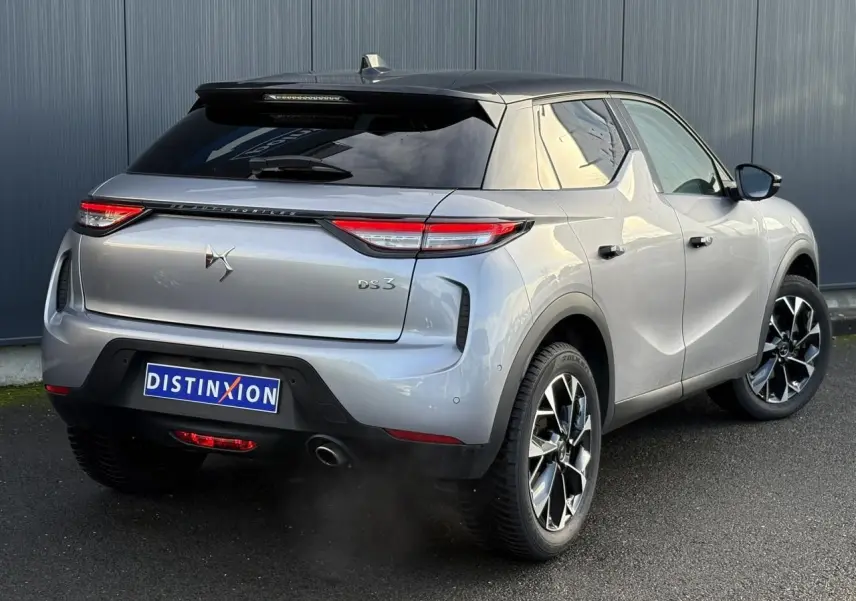 Vue 3/4 arrière droite d'un DS3 2024 gris Artense avec toit noir et jantes alliage noires et argentées.