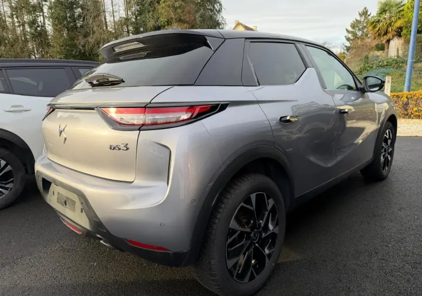 Vue 3/4 arrière droite d'une DS3 2024 gris Artense avec toit noir et jantes alliage noires.