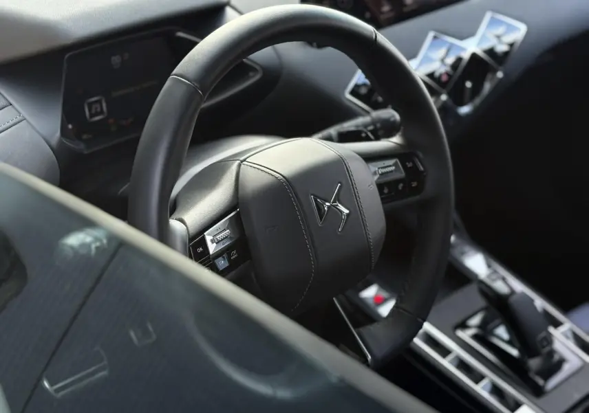 Vue rapprochée du volant cuir noir et du tableau de bord numérique intérieur du DS3 2024.