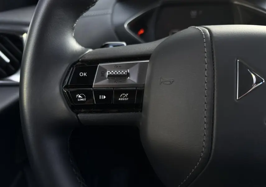 Gros plan sur le volant cuir noir du DS3 2024 avec commandes intégrées pour régulateur adaptatif et assistance.