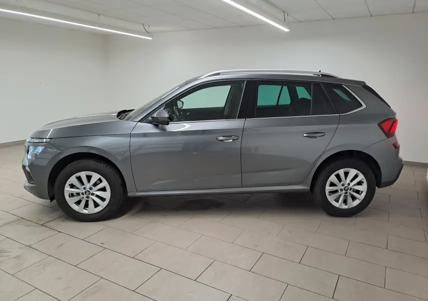 Vue de profil côté gauche d'un Skoda Kamiq gris graphite 2025 avec jantes alliage et caméra de recul intégrée.