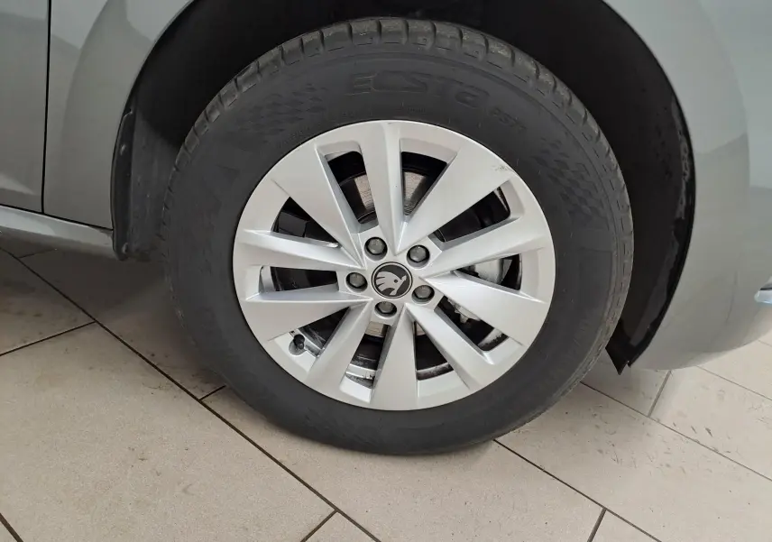Gros plan sur la roue avant gauche d’un Skoda Kamiq gris graphite, mettant en valeur la jante alliage et le pneu.