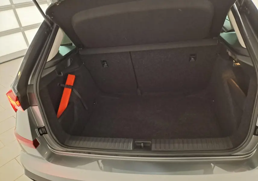 Coffre ouvert vu de l'arrière d'un Skoda Kamiq gris graphite 2025, avec tapis noir et triangle de sécurité orange.
