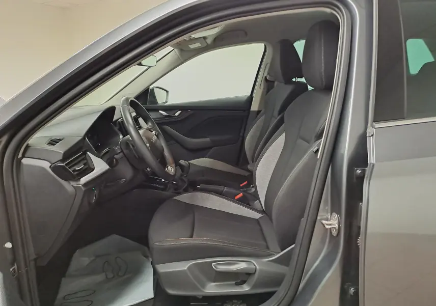 Vue intérieure côté conducteur du Skoda Kamiq gris graphite 2025, sièges tissu bicolore et tableau de bord moderne.