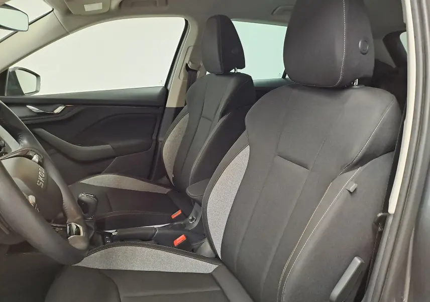 Vue intérieure côté conducteur du Skoda Kamiq 2025, sièges tissu bi-ton gris et noir avec surpiqûres contrastées.