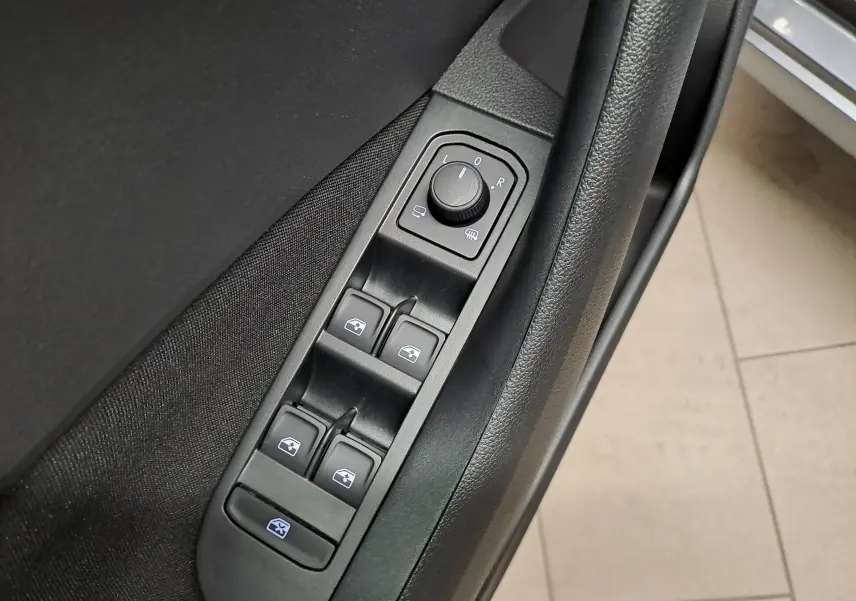 Gros plan sur les commandes de lève-vitres et réglage des rétroviseurs côté conducteur du Skoda Kamiq gris graphite 2025.