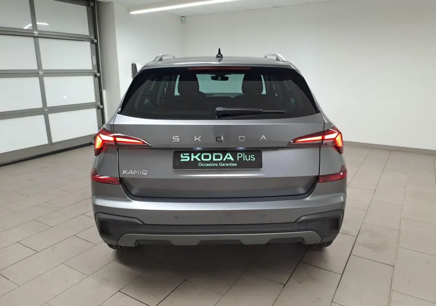 Vue arrière d'un Skoda Kamiq gris graphite 2025 avec feux allumés et caméra de recul visible sous le logo.