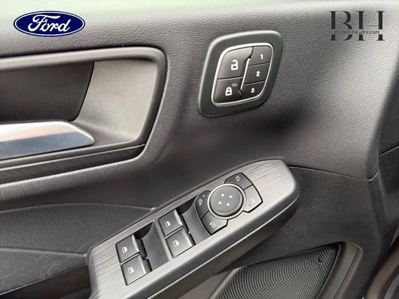 Détail de la porte avant gauche du Ford Kuga 2024 gris Solar avec commandes de vitres et verrouillage centralisé.