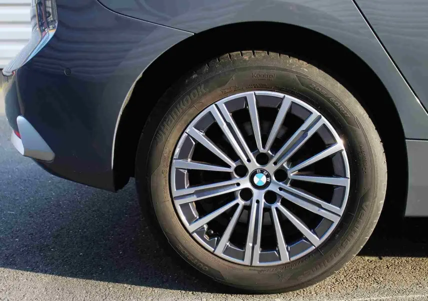 Gros plan sur la roue arrière droite d’une BMW Série 2 Active Tourer gris Nardo, jante alliage multi-branches.