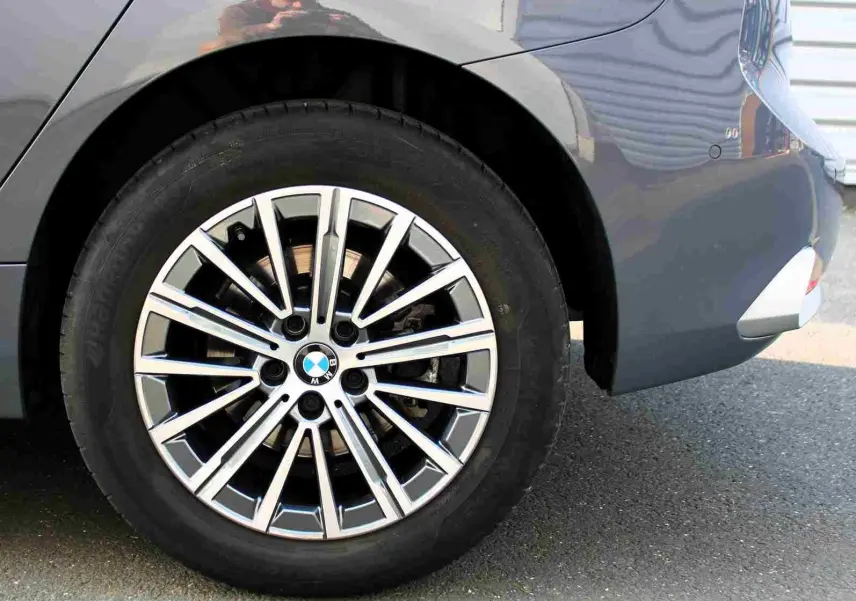 Gros plan sur la roue arrière droite d’une BMW Série 2 Active Tourer gris Nardo métal avec jante alliage multi-branches.
