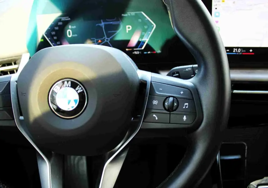 Gros plan sur le volant cuir noir de la BMW Série 2 Active Tourer 2023 avec commandes intégrées et tableau de bord digital.