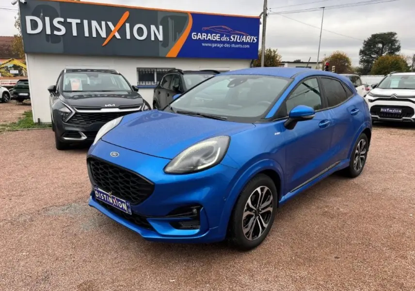Ford Puma bleu 3/4 avant droit, avec jantes alliage noires et vitres arrière surteintées, sur parking extérieur.