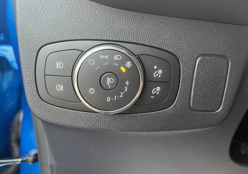 Gros plan sur la molette de réglage des phares du Ford Puma bleu 2022, avec commandes d'éclairage et antibrouillard.