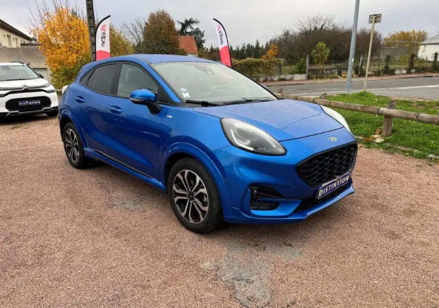 Ford Puma bleu métallisé en vue 3/4 avant droit, avec jantes alliage noires et vitres arrière surteintées.