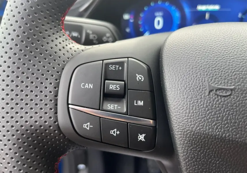 Gros plan sur les commandes de régulateur de vitesse et volume au volant perforé du Ford Puma 2022.
