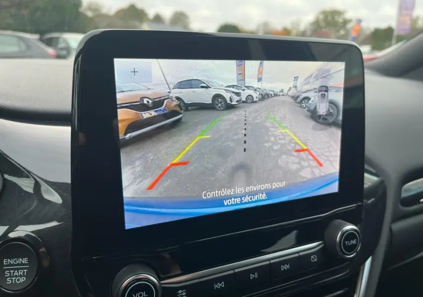 Écran tactile intérieur montrant la caméra de recul du Ford Puma bleu avec lignes d’aide au stationnement colorées.