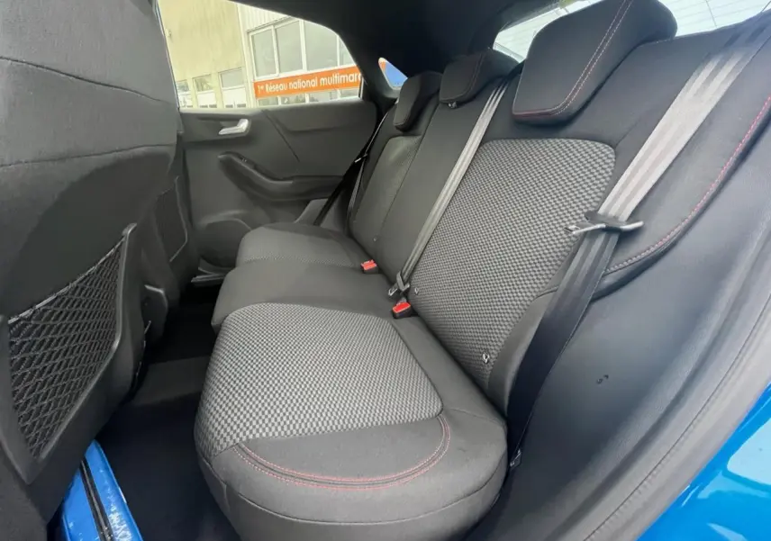 Vue intérieure côté droit sur la banquette arrière noire avec surpiqûres rouges du Ford Puma bleu 2022.