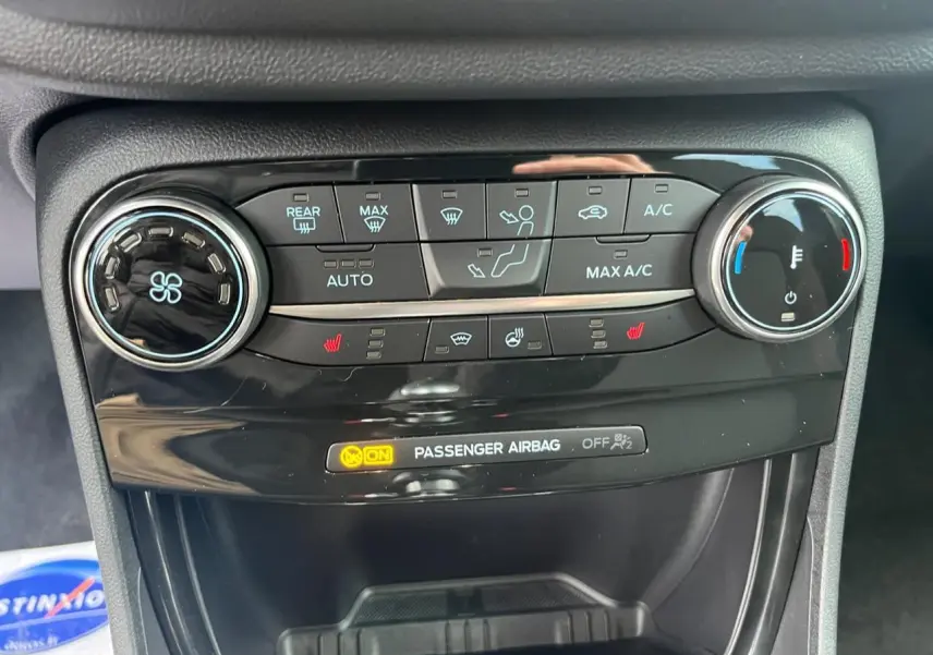 Vue rapprochée de la console de climatisation du Ford Puma bleu, avec commandes digitales et réglages chauffants visibles.