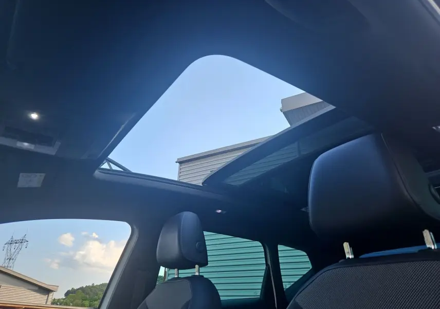 Vue intérieure du toit panoramique ouvert et des sièges avant en cuir noir du SEAT Ateca blanc 2018.