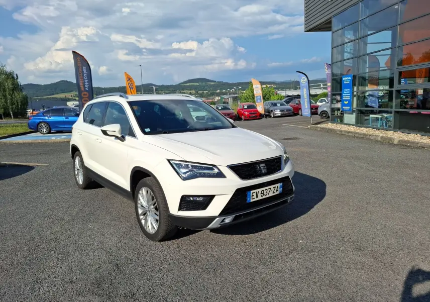 Vue 3/4 avant d’un SUV SEAT Ateca blanc avec jantes alliage 18 pouces, sur parking extérieur ensoleillé.