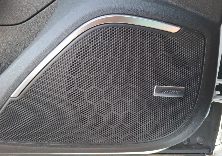 Gros plan sur l'enceinte Bose intégrée à la porte avant droite d'une Renault Mégane blanche.