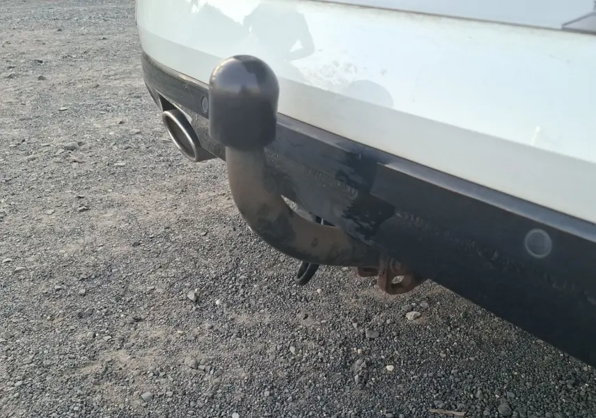 Gros plan sur l'attelage arrière noir d'une Renault Mégane blanche, avec sortie d'échappement visible à gauche.