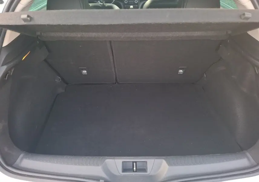 Coffre ouvert vu de l'arrière d'une Renault Mégane blanche, espace de chargement vide et habillage intérieur noir.