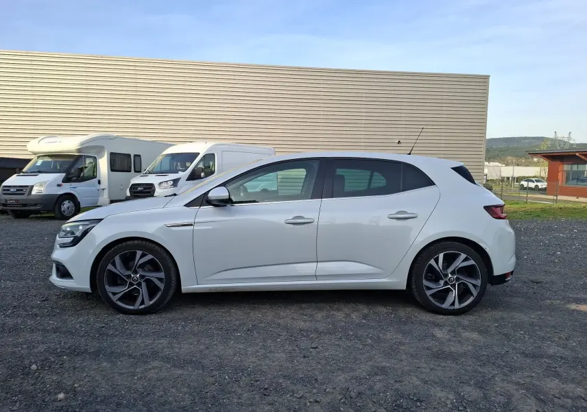 Vue de profil côté gauche d'une Renault Mégane blanche de 2016 avec jantes alliage et vitres teintées.