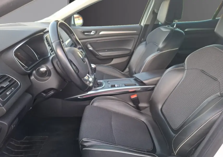 Intérieur avant droit de la Renault Mégane blanc, sièges en cuir noir avec coutures blanches et tableau de bord moderne.