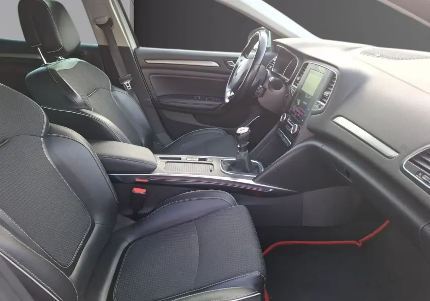 Vue intérieure côté conducteur de la Renault Mégane 1.6 DCI 130 Energy Intens 2016 avec sièges noirs et console centrale manuelle.