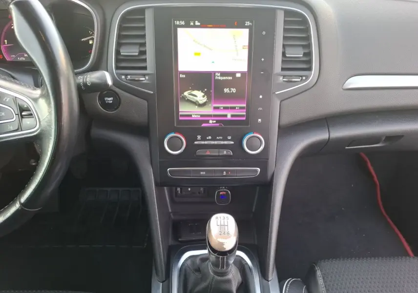 Vue intérieure centrée sur la console centrale et levier de vitesses manuelle d'une Renault Mégane blanche de 2016.