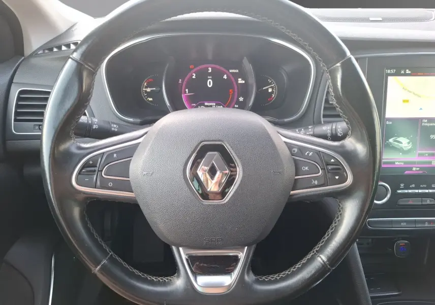 Vue rapprochée du volant noir de la Renault Mégane 1.6 DCI 130 Energy Intens avec tableau de bord numérique et écran tactile.