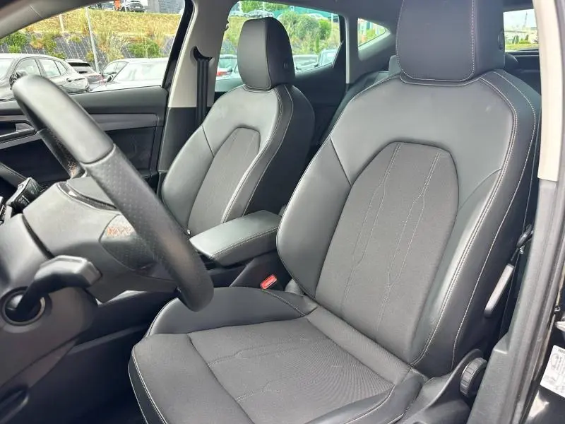 Vue intérieure des sièges avant en tissu et similicuir noir du CUPRA Formentor 1.5 TSI 2024, avec accoudoir central.