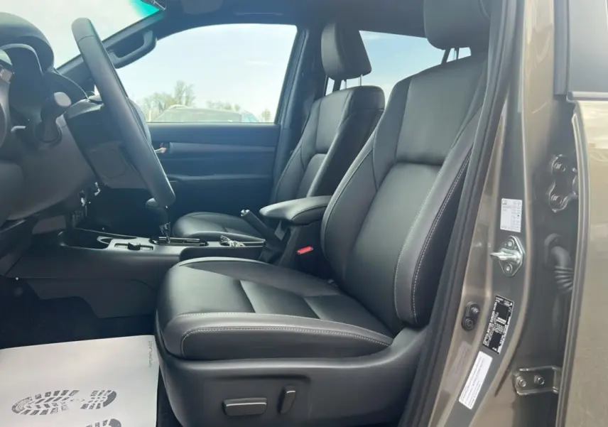 Intérieur côté conducteur du Toyota Hilux 2025 en bronze impérial, sièges cuir noirs et boîte automatique visible.