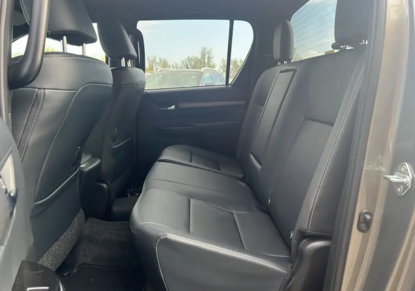 Vue intérieure côté droit montrant la banquette arrière en cuir noir du Toyota Hilux 4x4 Invincible 2025 bronze impérial.