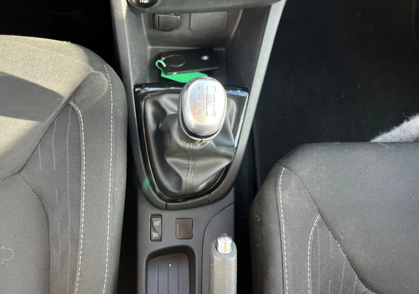 Vue plongeante sur la console centrale d'une Renault Clio IV 2019 avec levier de vitesse manuel et sièges tissu noirs.