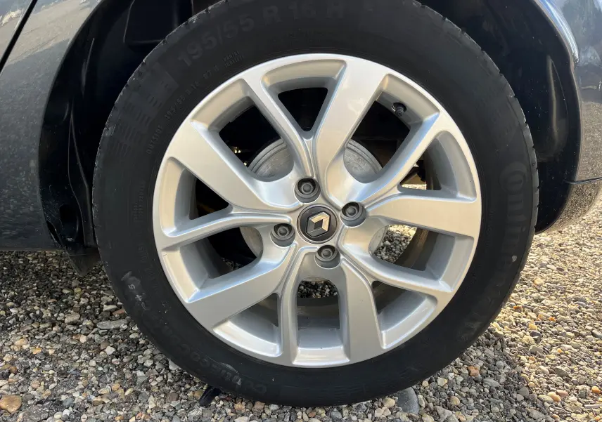 Gros plan sur la jante alliage argentée avec logo Renault au centre d'une Renault Clio IV diesel bleue.