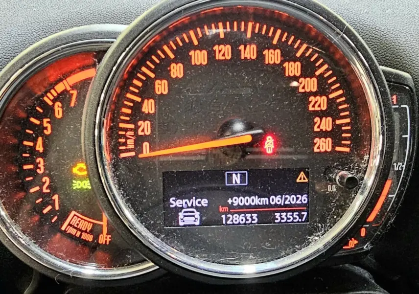 Gros plan sur le tableau de bord du MINI Cooper Countryman rouge, affichant le compteur de vitesse et le compte-tours éclairés en orange.