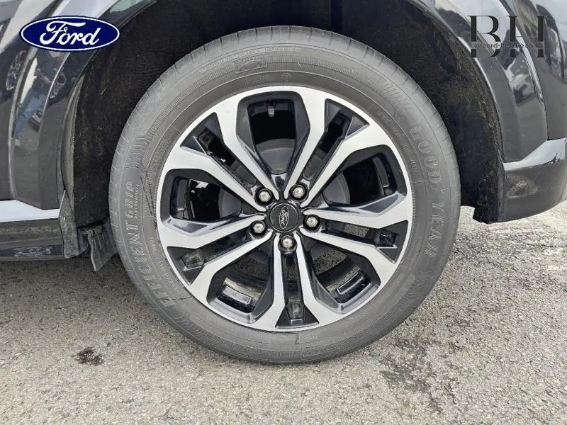 Gros plan sur la roue avant droite avec jante alliage bicolore du Ford Puma noir Agate Métallisée 2021.