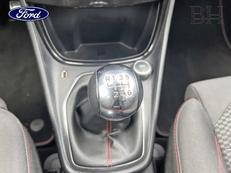 Gros plan sur le levier de vitesses manuel chromé avec coutures rouges dans l'habitacle noir du Ford Puma 2021.