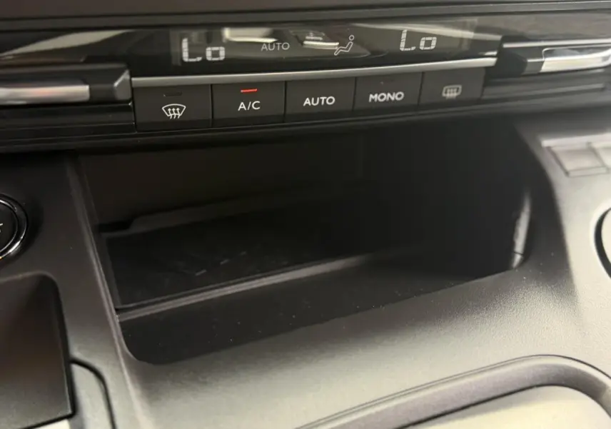 Gros plan sur la console centrale du Peugeot Rifter 2026, montrant les commandes de climatisation automatique et un espace de rangement noir.