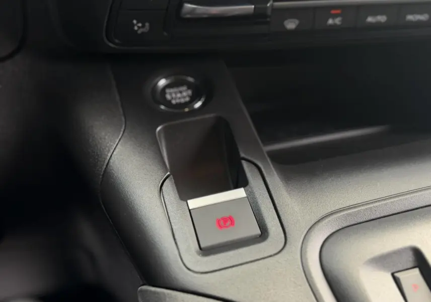 Gros plan sur le frein de stationnement électrique et le bouton start/stop dans l’habitacle noir du Peugeot Rifter 2026.