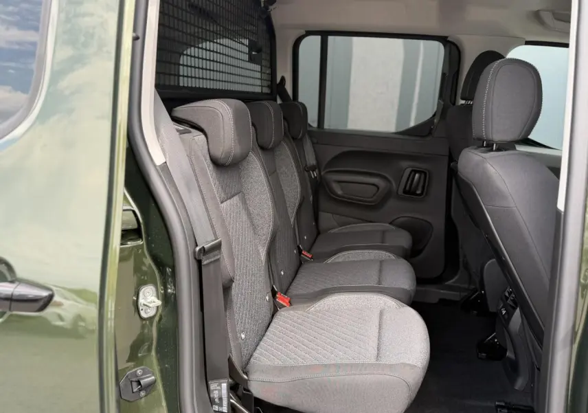 Vue latérale intérieure sur les trois sièges individuels arrière gris du Peugeot Rifter Vert Sirkka avec porte coulissante ouverte.