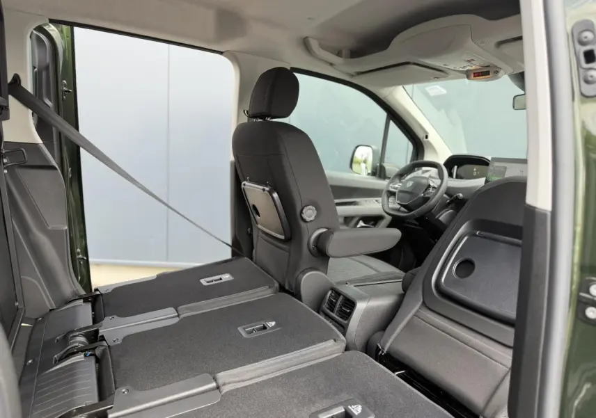 Vue intérieure côté droit du Peugeot Rifter Vert Sirkka 2026, sièges arrière rabattus et siège avant en tissu noir.