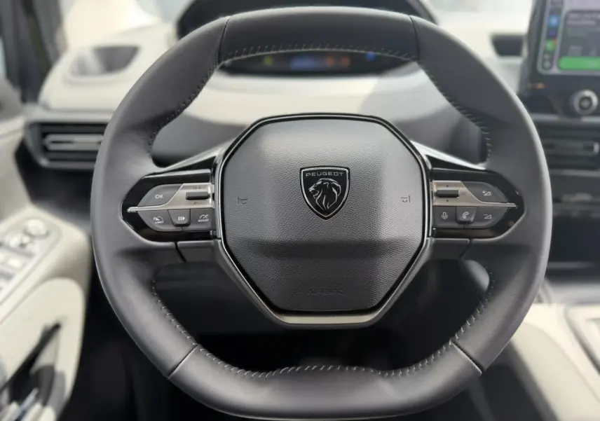 Vue rapprochée du volant cuir multifonction noir du Peugeot Rifter 2026, avec commandes intégrées et logo central lion.