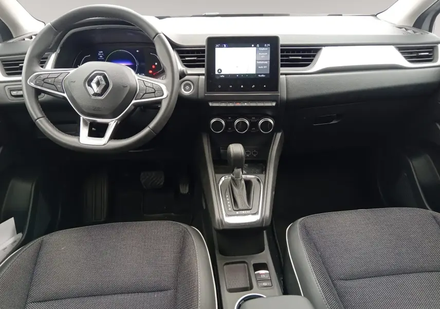 Vue intérieure frontale du tableau de bord du Renault Captur E-Tech hybride, avec écran tactile et volant multifonction.
