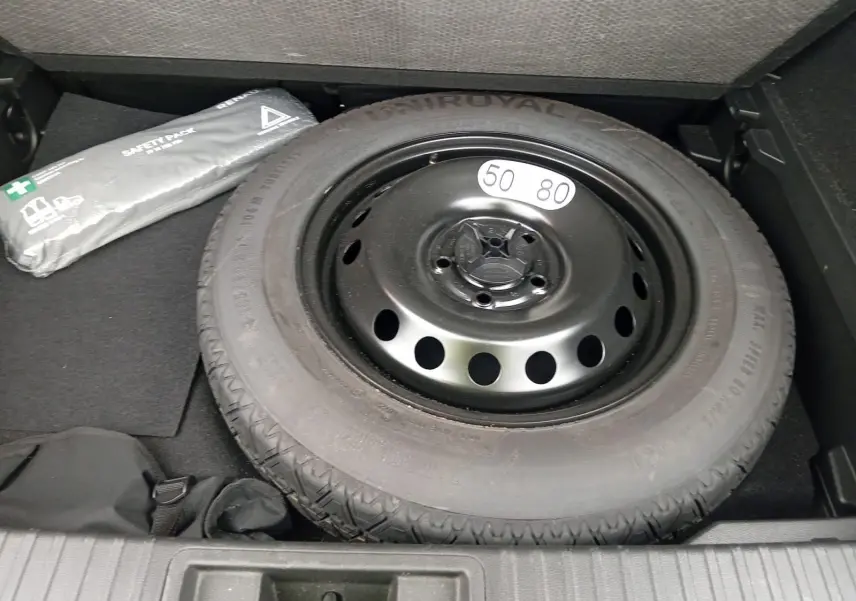 Pneu de secours noir avec étiquette 50-80 dans le coffre d'un Renault Captur gris alu/noir 2023.