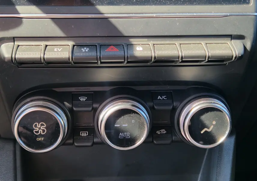 Gros plan sur les commandes de climatisation et boutons de fonction du tableau de bord du Renault Captur gris alu/noir 2023.